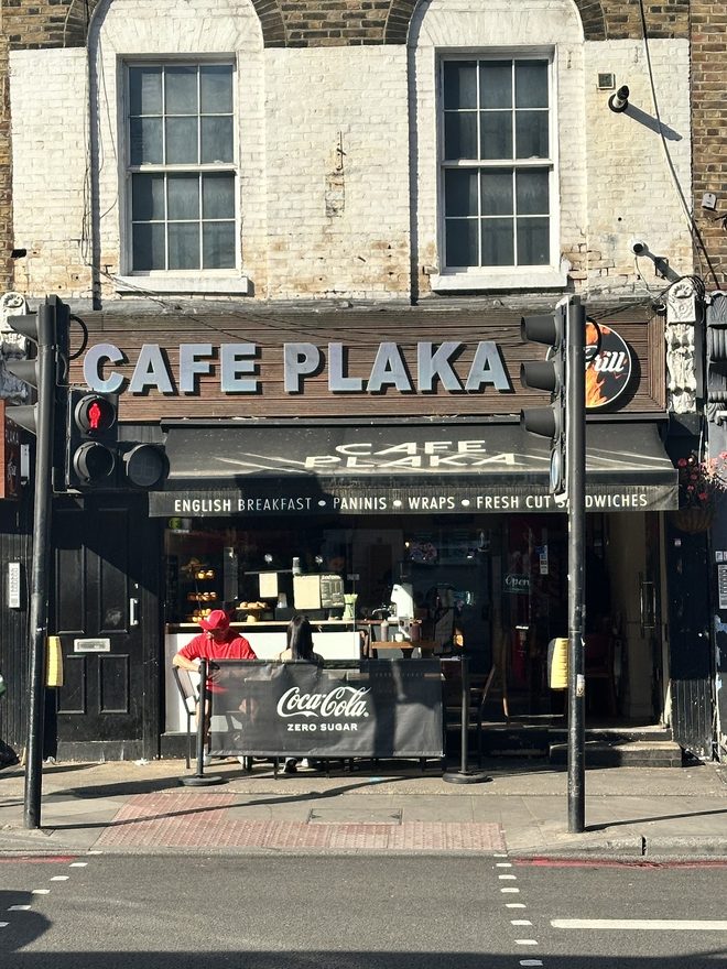 The Cafe Plaka shopfront under its black awning.