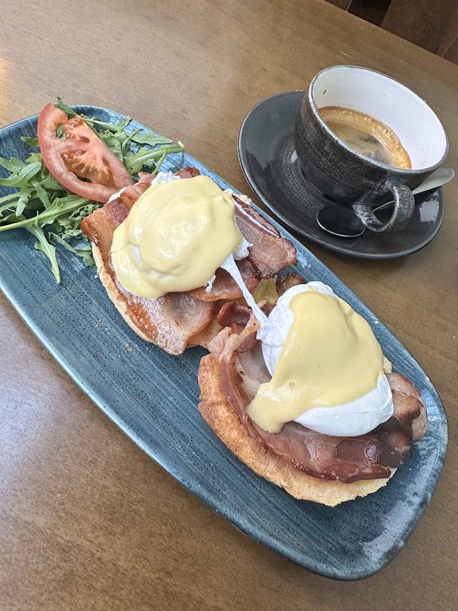 Eggs Benedict with a cappuccino behind.