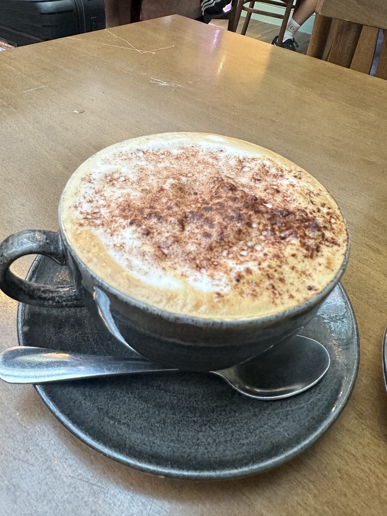 Cappuccino in a grey cup on a wooden table.